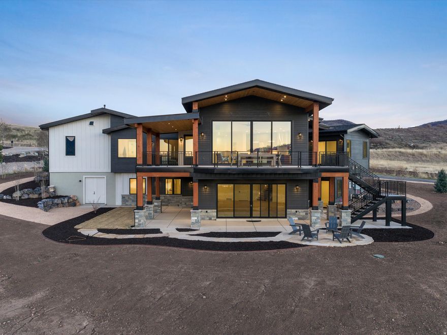 Perched above Ogden Valley in the exclusive Trappers Crossing development, this luxurious 4,820 sq ft mountain residence offers unobstructed views of Snowbasin Ski Resort and Pineview Reservoir, elevated further by Snowbasin's selection as a 2034 Winter Olympic venue. Brand new construction, this custom build is designed with a seamless blend of refined mountain architecture and modern performance. Five bedrooms, six bathrooms, vaulted ceilings, expansive windows, and an open-concept great room to frame the views while creating an ideal setting for everyday living and entertaining. The chef's kitchen features top-tier SKS appliances, dual-fuel gas/electric range, dual dishwashers, Taj Mahal stone surfaces, and direct deck access for outdoor grilling and indoor-outdoor dining. The primary suite is a private retreat with deck access, radiant-heated floors, steam shower, and spa-quality finishes. The walkout lower level is designed as a destination, offering 10-foot ceilings, a fireplace, wet bar with ice maker, and indoor/outdoor bath access to the future spa and pool. A 1,456 sq ft four car garage with RV/boat capable tandem bay, EV charging, radiant heat, and golf simulator wired. Advanced systems including dual fuel heat pumps, fully modulated HVAC, smart thermostats, security wiring, ready for powered blinds, and generator installed. Development owned well and sewer with protected open space, four-season recreation, Olympic legacy proximity, and unmatched views, this Trappers Ridge estate represents a rare opportunity to own a luxury mountain home in one of Utah's most exclusive alpine communities. Square footage figures are provided as a courtesy estimate only. Buyer is advised to obtain an independent measurement.