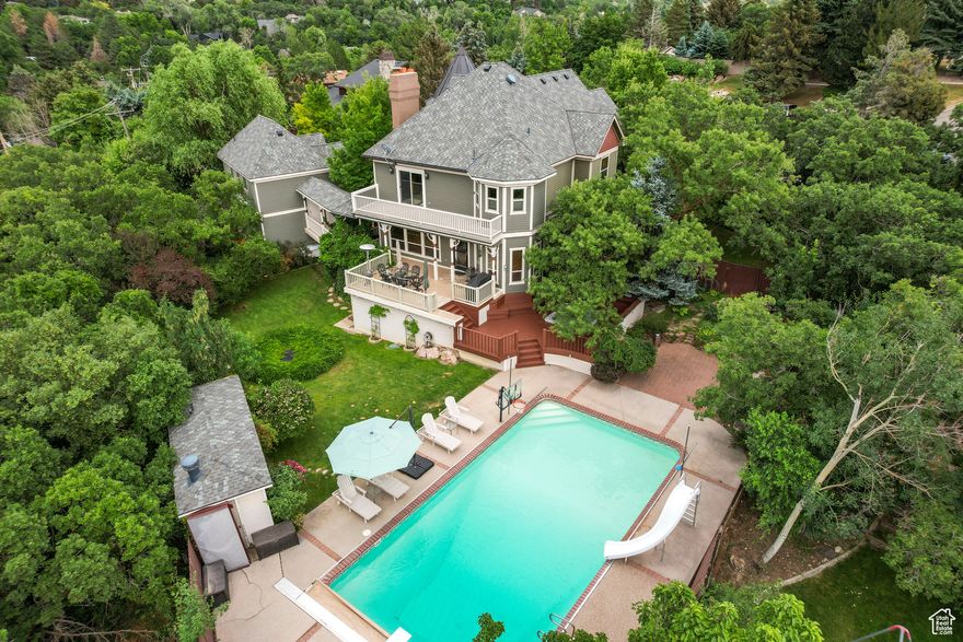 There are houses, and then there are experiences. This Victorian masterpiece, full of built-in antiques, in Uintah Highlands feels like something out of a storybook, delivering a lifestyle of beauty, privacy, and enchantment that's impossible to replicate. Tucked away on a secluded, wooded lot, this home captures sweeping mountain and valley views while wrapping you in timeless charm. From the moment you step onto the iconic wrap-around porch, you'll feel the magic. The recently remodeled kitchen, with its perfect blend of modern sophistication and classic elegance, sets the tone for a home that is equally suited for quiet mornings and unforgettable gatherings. The backyard is a private resort, alive with wonder: a sparkling swimming pool for sun-soaked afternoons, a koi pond for peaceful reflection, a built-in hot tub for starlit evenings, and a gas firepit for cozy nights with friends and family. A quaint pool house with a  bath (not listed in the room count) adds convenience and character, while the bonus level (listed as level 3) above the 4-car garage offers endless possibilities, a creative studio, guest retreat, or home gym, just to name a few. Every corner of this home tells a story. Every detail, from its architecture to its secluded setting, speaks of craftsmanship, style, and soul. There's nothing cookie-cutter here, only the rare chance to own a home with a personality as vibrant and unique as the fairytales that inspired it. This is not just a place to live. It's a place to dream, a place to gather, and a place to create memories that last a lifetime.