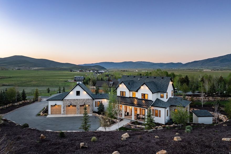 Refined Country Living Near Park City with Forever Scenic Views This custom modern farmhouse, featured in the Park City Showcase of Homes, is situated adjacent to Ure Ranch, an 835-acre preserved agricultural heritage ranch offering forever protected views, open space, and abundant wildlife habitat. Located at the entrance of Kamas Valley near Ballerina Farm and just 15 minutes from downtown Park City, the privately gated property combines quiet country serenity with convenient access to skiing, golf, hiking, biking, fishing, dining, and year-round recreation right outside your door. Offered furnished and exceptionally well cared for, the home blends timeless farmhouse character with polished modern design through a warm palette of wood, brick, stone, and steel. The grounds are beautifully designed with soft rolling green landscaping, mature trees, multiple patios and decks, a private hot tub retreat, designer shed, and a stone walkway leading to a scenic overlook gazebo with sweeping valley views. Thoughtful outdoor gathering spaces create a true sense of privacy and connection to the surrounding landscape. Filled with natural light and designed for effortless main-level living, the home features a spacious great room, chef's kitchen, and seamless indoor-outdoor living spaces ideal for entertaining or peaceful evenings at home. The main-level primary suite offers serene mountain views, a spa-inspired bath with soaking tub and oversized shower, and a generous walk-in closet. Upstairs are two guest bedrooms and a dedicated office with elevated views and abundant natural light. The walk-out lower level is designed for entertaining with a spacious family room, wet bar, game area, theater room, and a hidden brick wine and whiskey room inspired by a 1920s speakeasy. Two additional guest bedrooms and flexible secondary living spaces provide comfort and privacy for family and guests. Buyers considering homes in Hideout or Tuhaye should add this exceptional Kamas Valley property to their list.