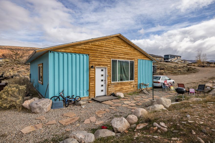 Imagine the possibilities with this one-of-a-kind container home set on 1.04 acres and surrounded by stunning red rock views. The 3-bedroom, 3-bath layout features an open living and kitchen area with built-in beds that offer a smart starting point for customization. A spacious detached garage/shop with office, kitchenette, and expansive upper-level space provides endless potential-whether for creative projects, additional living space, or the ultimate adventure basecamp. A rare opportunity to shape a truly personalized dream home in the heart of Moab's iconic landscape.  Square footage figures are provided as a courtesy estimate only and were obtained from images.  Buyer is advised to obtain an independent measurement.