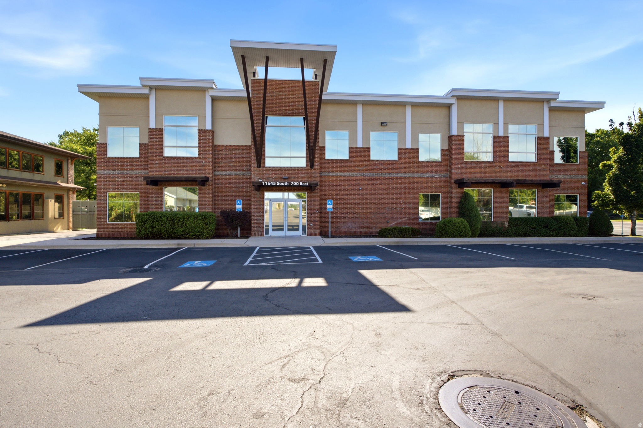 Two-story commercial building featuring brick and stucco facade, a prominent central entrance with double glass doors, and expansive windows