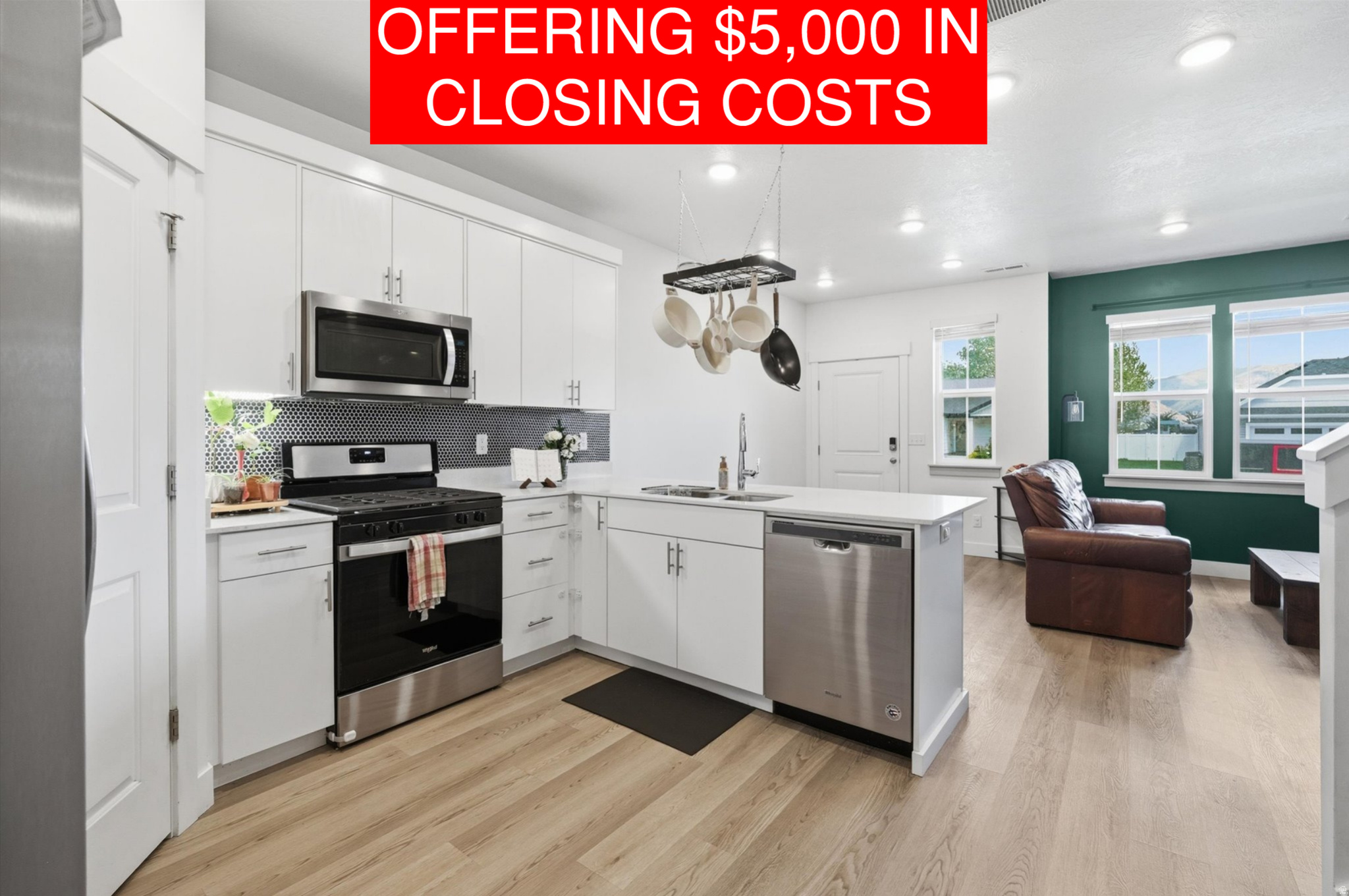 Open-concept kitchen featuring white cabinetry, stainless steel appliances, and wood-finish flooring