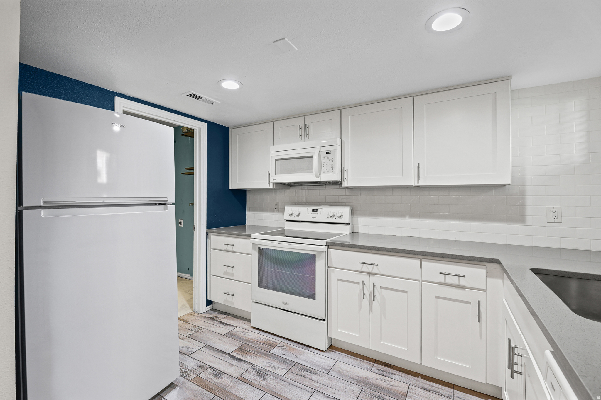 kitchen with white shaker cabinetry, subway tile backsplash, and solid surface countertops.