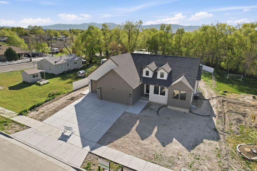 This brand-new rambler is nestled in the quiet rural community of Lake Point, just 30 minutes from Salt Lake City. The home showcases high-end finishes throughout, including a Craftsman-style exterior, custom cabinetry with soft-close doors, stainless steel appliances, double ovens, a gas cooktop, and a cozy gas fireplace. The expansive great room is highlighted by soaring 11-foot ceilings with grid-style stained wood beams, creating a warm yet elegant atmosphere. Enjoy the peaceful setting from the spacious 17x19 covered Trex deck, complete with black steel railing and a gas line stub-perfect for outdoor entertaining. The unfinished basement offers incredible potential and is already configured for three additional bedrooms, one bathroom, and a future wet bar.