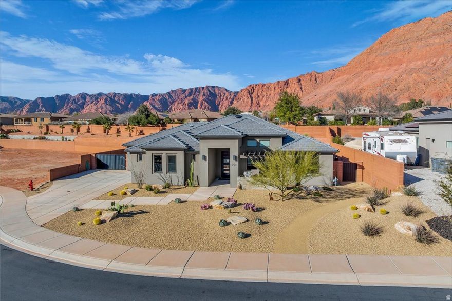 Stunning modern home showcasing beautiful Red Mountain backdrop. The open concept layout features a spacious living area with floor to ceiling fireplace and oversized sliding glass doors for indoor/outdoor living. The gourmet kitchen offers a large island, quartz countertop, custom cabinetry, high end appliances with gas cooktop and wall oven. The private primary suite is a true retreat with spa inspired bath featuring dual vanities, soaking tub and walk in shower. Step outside to an outdoor oasis with covered patio, large awning for outdoor kitchen, low maintenance turf and well manicured landscaping. Oversized garage with extra deep bay for a total of 4 cars plus large RV pad with gate. Luxury, Red Mountain backdrop and modern design come together in this exceptional property.