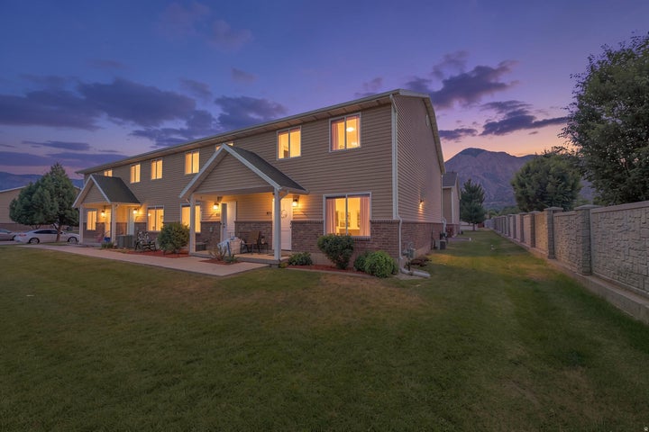 Two-story multi-unit dwelling with light tan siding and a brick-finish lower facade