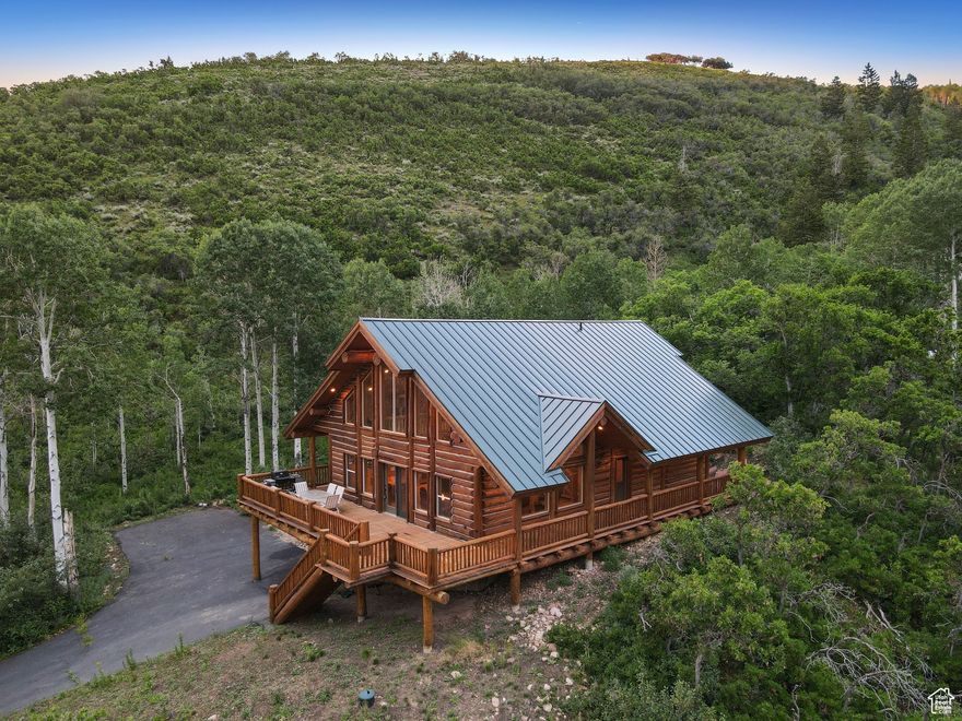 Discover your private mountain sanctuary atop Pine Mountain, where luxury meets wilderness in this extraordinary 4,182-square-foot craftsman log cabin. This stunning 5-bedroom, 3-bathroom retreat sits majestically on 0.81 acres overlooking the Weber Canyon, complemented by an additional 2.25-acre buildable lot-offering endless possibilities to build another cabin or maintain ultimate privacy. Built in 2004, this architectural marvel showcases the artistry of hand-cut logs and custom log supports that create an atmosphere of refined rustic elegance. Soaring ceilings throughout blend seamlessly with rich wood finishes, striking the perfect balance between modern comfort and authentic mountain charm.  The thoughtfully designed layout maximizes both space and views across three levels. The basement level provides an inviting living space with two comfortable bedrooms and a full bathroom, while the main level features a spectacular open-concept design with two additional bedrooms, an updated kitchen, and the home's crowning jewel-a floor-to-ceiling stone fireplace that commands attention and creates the perfect gathering space. The upper level offers a private loft retreat and luxurious primary suite complete with a spa-like bathroom featuring a jetted tub, elegant tile shower, and exclusive private deck access.  The expansive front deck serves as your personal theater for nature's nightly show, offering sweeping views down Weber Canyon and unrivaled sunset vistas to the west. Additional covered side decks extend your living space outdoors, perfect for morning coffee or evening relaxation. Practical amenities include an attached single-car garage plus abundant additional parking for guests and recreational vehicles.  Located in the highly coveted Pine Mountain area of Weber Canyon, residents enjoy paved road access for convenience while maintaining seasonal accessibility that preserves the area's pristine, secluded character. The community offers direct national forest access for unlimited outdoor recreation, tennis courts, and private horse pasture facilities, making it a true haven for outdoor enthusiasts.  This rare offering combines the tranquility of mountain living with thoughtful amenities and expansion potential. Whether seeking a primary residence, vacation retreat, or investment opportunity, this exceptional property delivers an unmatched mountain lifestyle experience. Contact us today to schedule your private showing of this remarkable Pine Mountain estate.