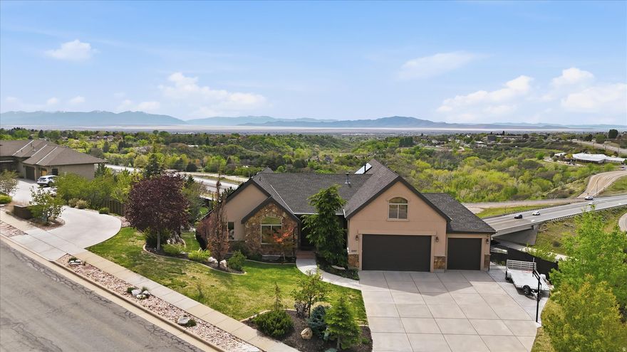 This Parade of Homes has amazing mountain and valley views to create a private oasis on a 1.10-acre lot. This home boasts beautiful trim work and built-in cabinetry throughout. The concrete fence around an area of the backyard provides privacy complete with a cozy pergola where you can sit by the fire and enjoy the sunsets in the evenings. Backyard has mature trees, a large raised garden (sprinklers have an app) next to a 12x18 shed with a roll-up garage door for storing outdoor equipment. Located on the East Layton bench, a short walk (200 ft) to the Bonneville Shoreline Trailhead. This home is truly made for both entertaining and everyday living, with jaw dropping views out all the back windows.  Enjoy an open floor plan, high ceilings and a chef's kitchen with stainless steel Thermador appliances, a basement kitchen/bar with Sub-Zero mini fridge. Main level features floor-to-ceiling windows, a generous primary suite, and additional bedroom (currently being used a an office). Upper level has a large bonus room, storage closets and a spacious bedroom with a view and walk in closet. The basement has 2 bedrooms (1 is currently being used as the exercise room) kitchen/bar, bathroom, living room and storage area. Wine enthusiasts will be delighted by the custom brick wine cellar (cold storage), complete with a barreled ceiling. Other notable features of this remarkable property include a three car oversized garage, a natural gas fire pit for cozy evenings outdoors, cement fence, drip watering system for trees on hill, Mitsubishi Electric solar panels for energy efficiency (around $50/month), remote blinds, a whole-home humidifier, a Kinetico soft water system, split HVAC system (furnace in the lower floor for main and lower level, furnace and & A/C in bonus level) and built in speakers throughout the home (Sonos Audio System w'app) for added convenience and entertainment and Jellyfish lighting for holiday lightening in various colors. Photo with property lines is approximate.