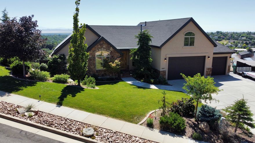 *More photos to come. This Parade of Homes home has amazing mountain and valley views to create a private oasis on a 1.10-acre lot. This home boasts beautiful trim work and built-in cabinetry throughout. The concrete fence around an area of the backyard provides privacy complete with a cozy pergola where you can sit by the fire and enjoy the sunsets in the evenings. Backyard has mature trees, a large raised garden (sprinklers have an app) next to a shed with a roll-up garage door for storing outdoor equipment. Located on the East Layton bench, a short walk (200 ft) to the Bonneville Shoreline Trailhead. This home is truly made for both entertaining and everyday living, with jaw dropping views out all the back windows.  Enjoy an open floor plan, high ceilings and a chef's kitchen with stainless steel Thermador appliances, a basement kitchen/bar with Sub-Zero mini fridge. Main level features floor-to-ceiling windows, a generous primary suite, and additional bedroom (currently being used a an office). Upper level has a large bonus room, storage closets and a spacious bedroom with a view and walk in closet. The basement has 2 bedrooms (1 is currently being used as the exercise room) kitchen/bar, bathroom, living room and storage area. Wine enthusiasts will be delighted by the custom brick wine cellar (cold storage), complete with a barreled ceiling. Other notable features of this remarkable property include a three car oversized garage, a natural gas fire pit for cozy evenings outdoors, cement fence, drip watering system for trees on hill, Mitsubishi Electric solar panels for energy efficiency (around $50/month), a whole-home humidifier, a Kinetico soft water system, split HVAC system (furnace in the lower floor for main and lower level, furnace and & A/C in bonus level) and built in speakers throughout the home (Sonos Audio System w'app) for added convenience and entertainment.