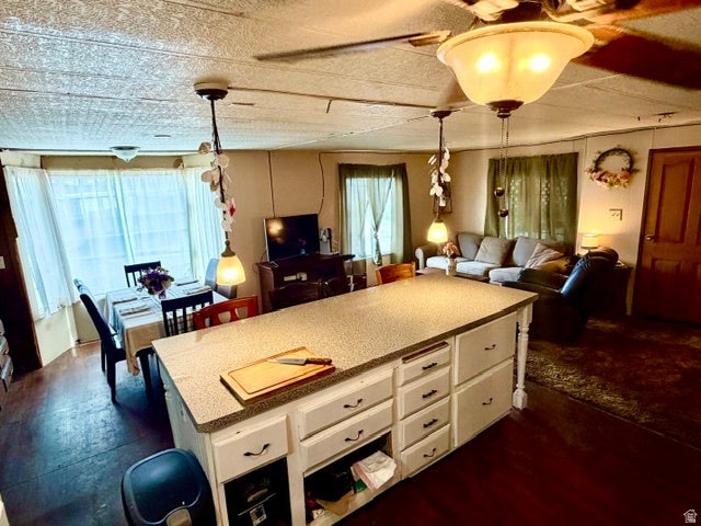 Kitchen island with white cabinetry and dark hardware, wood-finish flooring, recessed lighting, and an open-concept layout