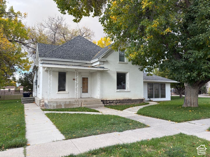 White painted brick exterior featuring a covered front porch with decorative metal columns, multi-gabled roofline, and…