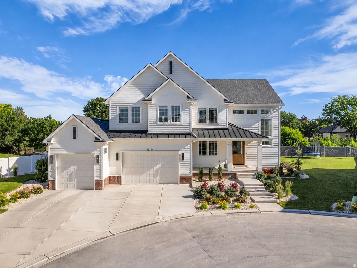 Modern farmhouse exterior featuring white horizontal siding, a dark asphalt shingle roof, and a prominent front entry with a wood door