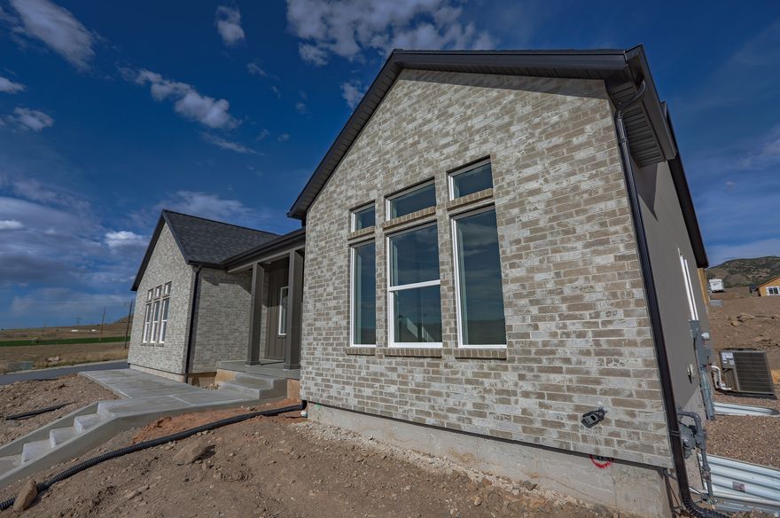 The pinnacle of modern living in this newly constructed masterpiece, perfectly situated in the elevated North Ridge Estates. This prime location offers the best of both worlds: serene mountainside living with unmatched convenience and beautiful sunset views, providing immediate access to I-15, local shopping, the Central Valley Medical Center, and local entertainment. Built to model specifications with over $82,000 in premium upgrades, the home features custom accent walls throughout, elegant decorative lighting, a gourmet kitchen equipped with real wood soft-close cabinetry, quartz countertops, and high-end LG appliances. Luxury continues into the master suite, with dual vanities, matte black and gold plumbing fixtures, and a separate soaking tub/shower with solid-surface surrounds. High-efficiency features like an Ecobee smart thermostat, 95% furnace, and on-demand instant water heater ensure year-round comfort, while the expansive covered back patio offers an extension of living space for entertaining with gorgeous sunsets. A professionally terraced front yard--a $14,000+ upgrade--with large rock retaining walls provide stunning curb appeal. Beyond its immediate luxury, this property is a powerful financial asset. The basement with lofty 9' ceilings is pre-plumbed for a full second kitchen, laundry, and bathroom, and features a dedicated separate entrance-specifically designed to be converted into a high-yield ADU or just more space for your family. Rental rates for a 1-2 bedroom basement apartment in the area are estimated at $1,200-$1,500/mo, substantially offsetting your mortgage and providing long-term financial flexibility. Whether you are looking for a spacious family home with model finishes or a smart investment that pays for itself, this property delivers on every level. Estimated completion date March 9th! Must see!