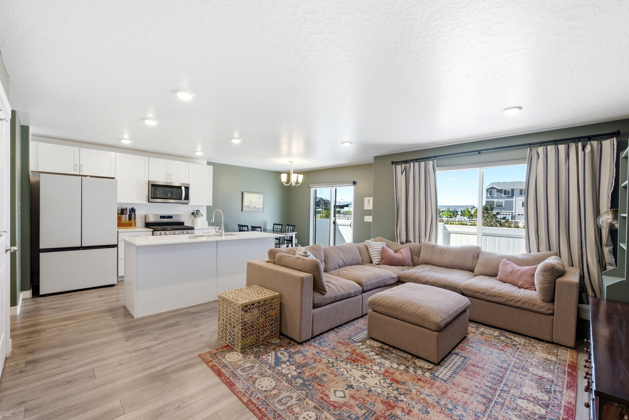 Open-concept living space featuring wood-finish flooring, recessed lighting, and a sliding glass door leading to an outdoor area