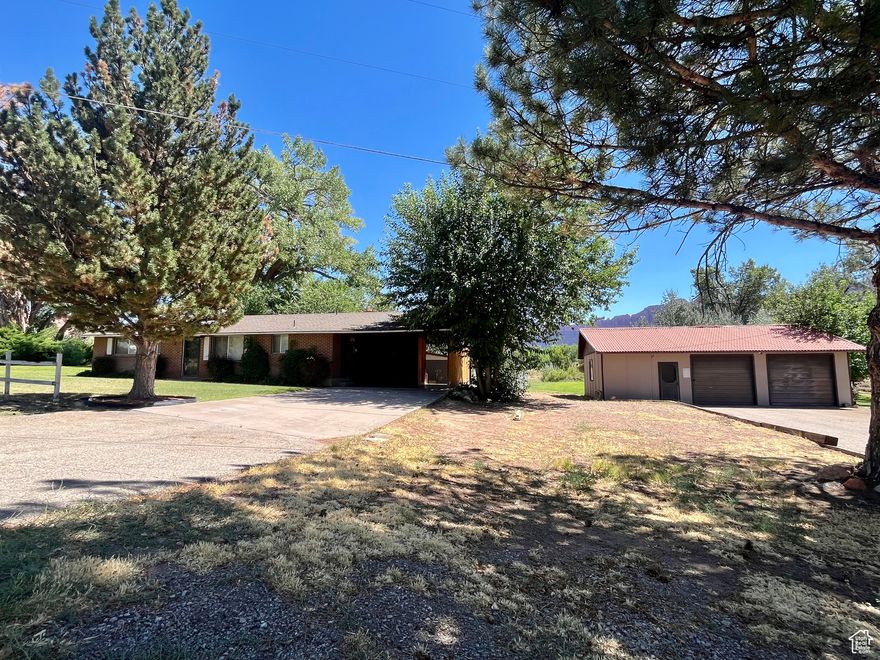 Incredible INVESTMENT PROPERTY OR PERSONAL RETREAT in one of Moab's most desirable areas! Situated on 1.45 lush acres near the Moab Golf Course, this well-maintained multi-unit rental property offers both comfort and flexibility. The main home features 2 bedrooms, 1 full bath, and 1,055 sq ft of stylish living space. Enjoy low-maintenance tile and laminate flooring throughout, custom cabinetry, granite countertops, and a cozy gas fireplace in the living room. A detached 2-car garage includes a charming 506 sq ft studio apartment - perfect for guests, tenants, or a private workspace. Each unit has separate power meters for convenience and flexibility. This expansive 1.45 acre parcel is a rare gem in Moab. It is beautifully landscaped with mature trees, sprawling grass, and stunning red rock views. There is plenty of room to expand or enjoy as-is. Whether you're looking for a full-time residence with rental income, a vacation property, or an investment in Moab's thriving market, this unique offering checks all the boxes!