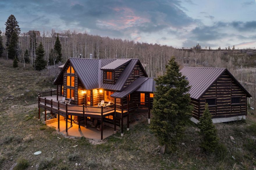 Perched on 2.68 acres featuring mature trees and dramatic rock formations, this stunning 4,068 square foot retreat is one of the most remarkable properties in Tollgate Canyon's Forest Meadows community. Oriented to capture sweeping 270-degree views of the Uinta Mountains and surrounding ski resorts, the cabin's massive front deck sets the tone the moment you arrive.  Step inside to an open floor plan designed to keep those views front and center. The great room anchors around a beautiful fireplace, while the main level primary suite opens directly onto the deck - seamlessly blending indoor comfort with the surrounding landscape. A well-appointed kitchen with granite countertops and a casual dining area round out the main level, all framed by the same breathtaking panorama.  Upstairs, a reading loft connects two bedrooms sharing a full bathroom - a perfect retreat for guests or family. The walkout basement expands the living space further with an additional bedroom, a bathroom featuring a steam shower, and a generous game room and TV area. Practical touches abound as well, including cold storage, an oversized laundry room, and a dedicated room with backup water tanks for added peace of mind.  Whether you're envisioning a cherished family legacy cabin, a high-performing nightly rental, or a full-time primary residence, this property delivers on every front. Radiant heat and an attached two-car garage add year-round comfort and convenience.  Tollgate Canyon offers the perfect mountain escape while being just moments away from modern conveniences - just 20 minutes from Whole Foods, 22 minutes from Deer Valley East Village, 29 minutes to Canyons Village Base, and 45 minutes from Salt Lake City International Airport.