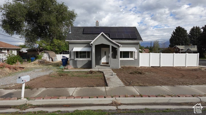 Charming single-story residence featuring a classic white exterior with dark roofing, front-facing covered entry, and…
