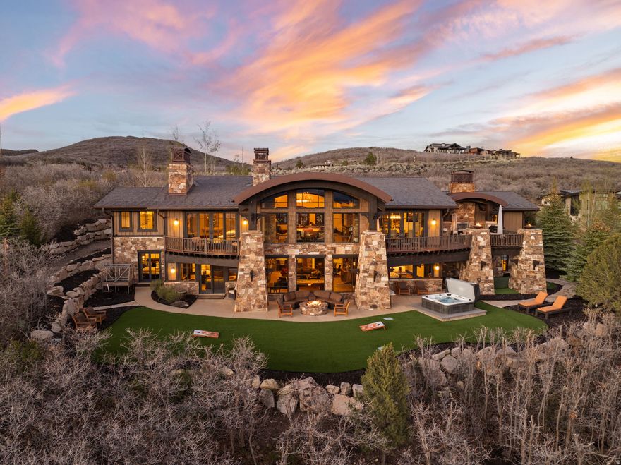 Experience breathtaking, unobstructed views of Deer Valley, Mount Timpanogos, Jordanelle Reservoir, and the Mark O'Meara Championship Golf Course from this exceptional 1.88 acre estate in Tuhaye. One of the few true estate-sized parcels, it borders open space on two sides, offering rare privacy and a dramatic natural backdrop. This 7,726 square foot, 7-bedroom, 8-bathroom residence blends contemporary design with mountain elegance, creating a warm and inviting setting for both entertaining and everyday living. A heated driveway and motor court lead to a striking boulder waterfall with a wrought iron bear sculpture, setting the tone for the craftsmanship found throughout. Inside, floor-to-ceiling windows capture sweeping views and fill the home with natural light. The great room features a grand stone fireplace, soaring wood-beamed copper painted barrel ceiling. The chef's kitchen includes Wolf and Sub-Zero appliances, dual dishwashers, a large island, opening to an expansive deck with a fireplace, fire bowls, built-in BBQ, and multiple gathering areas. The main-level primary suite offers a private retreat with its own fireplace, deck access, and a spa-like bath with heated floors, steam shower, and soaking tub. The lower level is designed for entertaining with a family room, game area, kitchenette, wine cellar, and theater. 5 ensuite guest bedrooms provide comfort and privacy. Outdoor living includes a saltwater hot tub, firepit, turf lawn, stone paths, and a putting green. $200,000 Talisker Club membership deposit is included, offering access to golf, skiing, dining, spa, and year-round recreation.