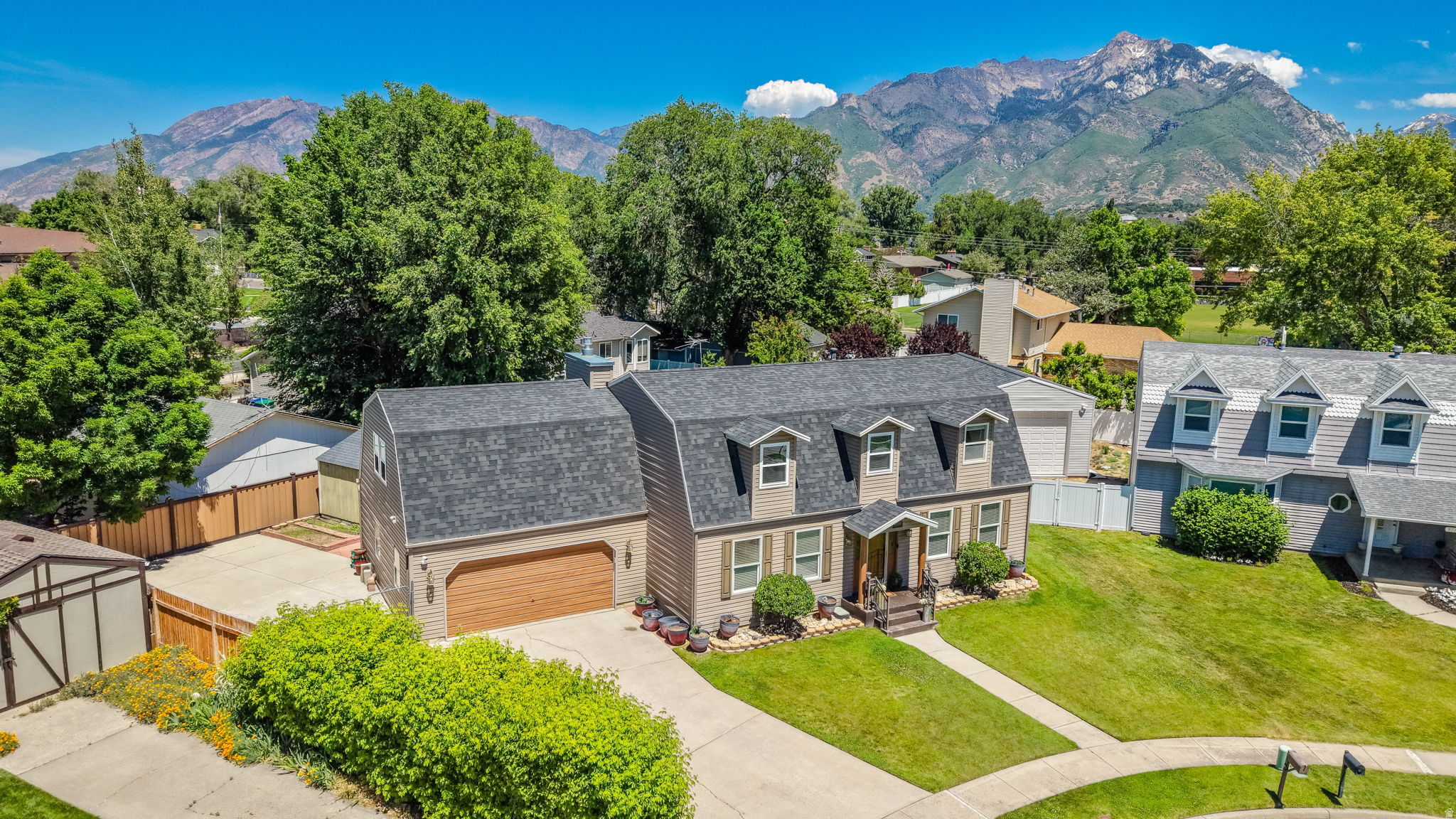 Two-story residence featuring dormer windows, a covered front entry, and a side-facing garage with a wood-finish door