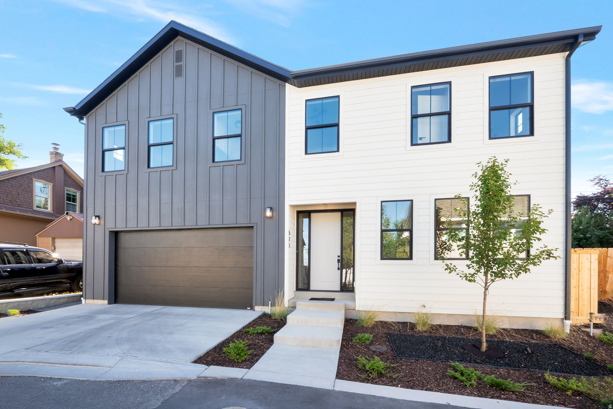 Modern two-story residence featuring a striking two-tone exterior with vertical board and batten siding alongside horizontal lap siding