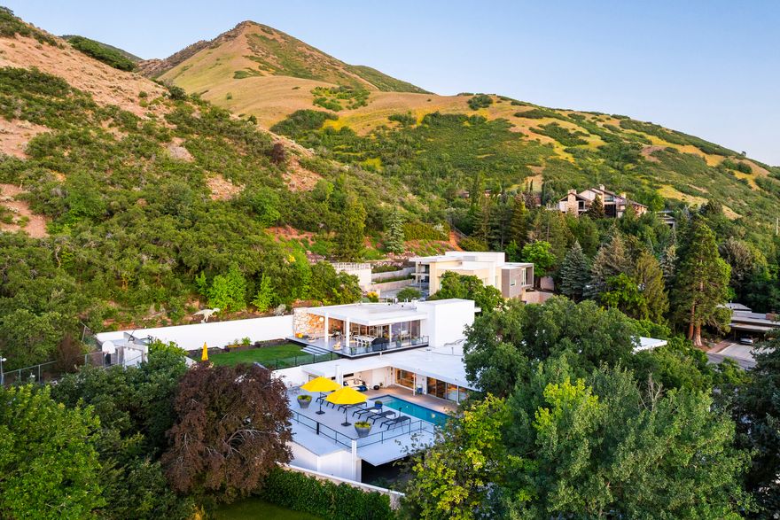Mid-Century Modern luxury home in Salt Lake City's highly sought-after St. Mary's neighborhood. Designed in 1957 by renowned Swiss architect Eduard Dreier, this architectural home sits on a private 0.55-acre cul-de-sac lot with panoramic views of downtown Salt Lake City and the Wasatch Mountains.  This fully restored 5,447 sq ft modern home blends historic architecture with contemporary upgrades, featuring exposed steel beams, expansive floor-to-ceiling windows, walls of glass, a cantilevered roofline, and natural stone accents. Ideal for buyers seeking a luxury modern home with architectural significance in Utah.  The property includes a 1,110 sq ft guest house (ADU) with glass and steel construction, designed in 2016, offering flexible space for guests or multigenerational living.  Outdoor amenities include a heated saltwater pool and spa, landscaped yard with mature trees, gardens, and multiple outdoor living and entertaining areas. The mountainside setting provides privacy while remaining minutes from downtown Salt Lake City, top-rated schools, hiking trails, and world-class skiing.  Interior features include two kitchens, custom walnut cabinetry, home office, gallery-style walls for art display, spa-inspired steam shower, and secure gated entry.  Rare opportunity to own a luxury architectural home in Salt Lake City with guest house, mountain views, and premium outdoor living.