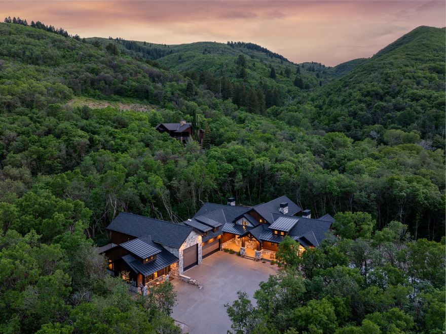 Set atop Pineview Overlook, this newly constructed 7,275-square-foot estate offers elevated mountain living on more than three acres of natural privacy, mature trees, and enduring craftsmanship. Thoughtfully designed with long-lasting materials and upscale amenities, the home includes radiant in-floor heating on both levels, engineered white oak flooring, and vaulted ceilings anchored by a dramatic wood-burning fireplace with a reclaimed Civil Warera mantel. The gourmet kitchen serves as a standout focal point, featuring white oak cabinetry, a painted island, a Wolf range, Sub-Zero appliances, and a walk-in pantry equipped with its own pebble ice machine. Just beyond, the expansive great room flows seamlessly to a welcoming outdoor patio-perfect for entertaining or unwinding by the fire. With four bedrooms and four bathrooms, the floor plan emphasizes comfort and convenience, offering multiple laundry spaces and a finished lower level outfitted with an entertainment room, wet bar, full vault, and abundant storage. Attached to the home is a private 606-square-foot casita complete with a full kitchen, full bath, laundry, and its own entrance-providing guests a fully independent and exceptionally comfortable retreat. The oversized, heated three-car garage includes a deep RV bay, interior access to the basement, and a utility sink, ensuring both practicality and warmth during the winter months. Bordered by protected open space and a seasonal creek, the property delivers a peaceful sense of seclusion while remaining just minutes from Pineview Reservoir, Powder Mountain, Snowbasin Resort, and Wolf Creek Golf Course. Frequent wildlife sightings, a level year-round accessible driveway, and unparalleled attention to detail make this residence a rare opportunity to experience luxury, comfort, and legacy living in one of Ogden Valley's most desirable settings. All property information, boundaries, and documents to be verified by buyer.