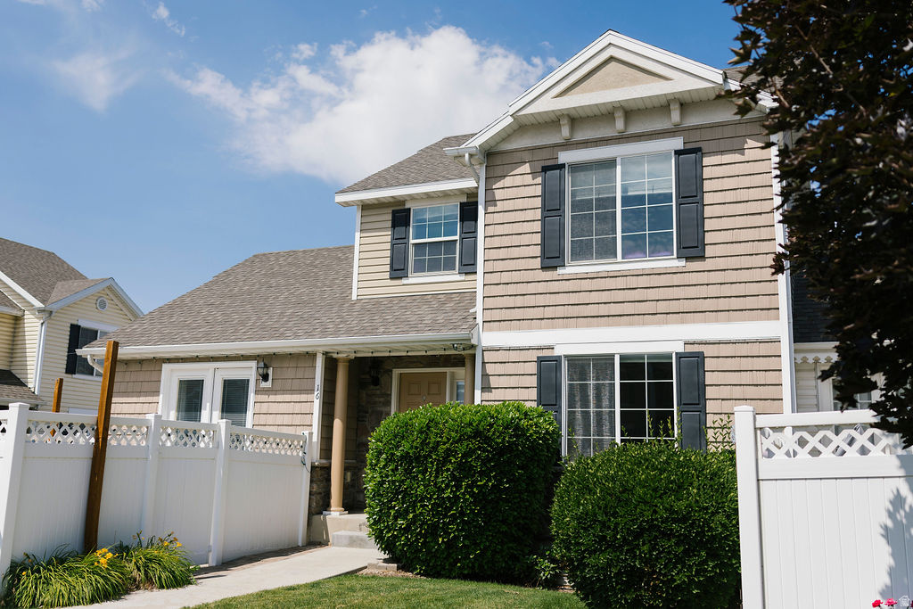 Two-story residence featuring light brown shingle siding and dark gray window shutters
