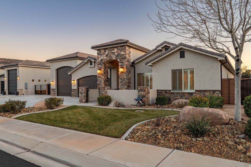 Located in Dixie Springs, near Sand Hollow State Park and within easy access to Zion National Park, this custom home offers exceptional indoor and outdoor living in a highly desirable Southern Utah setting. A welcoming courtyard entrance leads to a grand entry and spacious great room featuring a cozy fireplace and open-concept design. The upgraded kitchen showcases granite countertops, stainless steel appliances, built-in oven and microwave, gas cooktop, and a striking tile backsplash. Wood-look tile flooring throughout adds a modern touch while providing durability and easy maintenance. The primary suite includes a walk-in tile shower, separate soaking tub, and an oversized walk-in closet. Plantation shutters throughout the home provide both natural light and privacy. Outdoor living is a standout feature, with a beautifully designed backyard space that includes accent lighting, a propane-connected fire pit, and ample room for gatherings and relaxation. The oversized RV garage offers built-in hookups and sewer connection, plus extensive shelving for storage. An additional concrete pad provides even more space for vehicles, equipment, or storage needs. This property combines quality finishes, functional design, and proximity to some of Southern Utah's most iconic recreation areas.