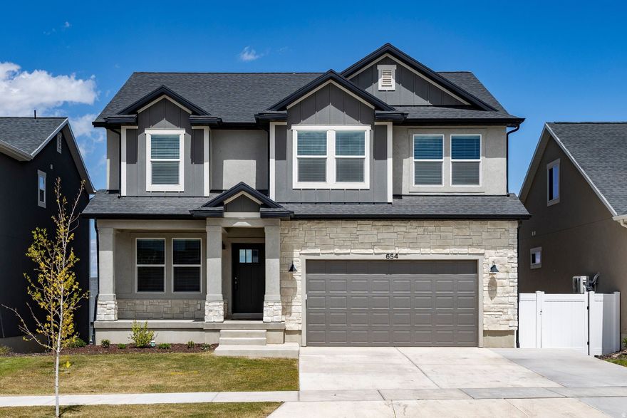 ** 1% closing cost credit available for qualified buyers using American Pacific Mortgage financing. Terms and conditions apply. Not all borrowers will qualify.** Experience the height of modern living in the prestigious Highridge community. Built in 2024, this stunning residence perfectly balances the "brand new" feel with the high-end finishes of a fully completed home. The main level is a showstopper, featuring vaulted ceilings and a fireplace that complement the moody, modern kitchen designed for entertaining. Windows flood the home with natural light and frame breathtaking views of the valley. Upstairs, French doors open to a spacious primary suite, complete with a bathroom and walk-in closet. Two additional bedrooms, a full bath, and a conveniently located laundry room round out the top floor. The upstairs was upgraded to 9ft ceilings. The walk-out basement features a fully equipped ADU or mother-in-law apartment, offering incredible flexibility for guests or rental income. The garage also has a built-out business opportunity, set up for dog grooming, but could easily be converted into a floral business, hair salon, or art studio. The shop is extra-insulated for comfort during the cold months. Options are endless! Just steps away, the amenities include a pool, clubhouse, gym, pickleball courts, and miles of trails. Conveniently close to great shopping located right off of Redwood Road, the Ranches Golf Club, Utah Lake, and newly connected UT-194, this location has it all.