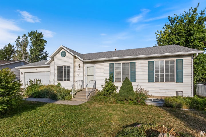 Ranch-style home with an attached garage, a shingled roof, and a front lawn