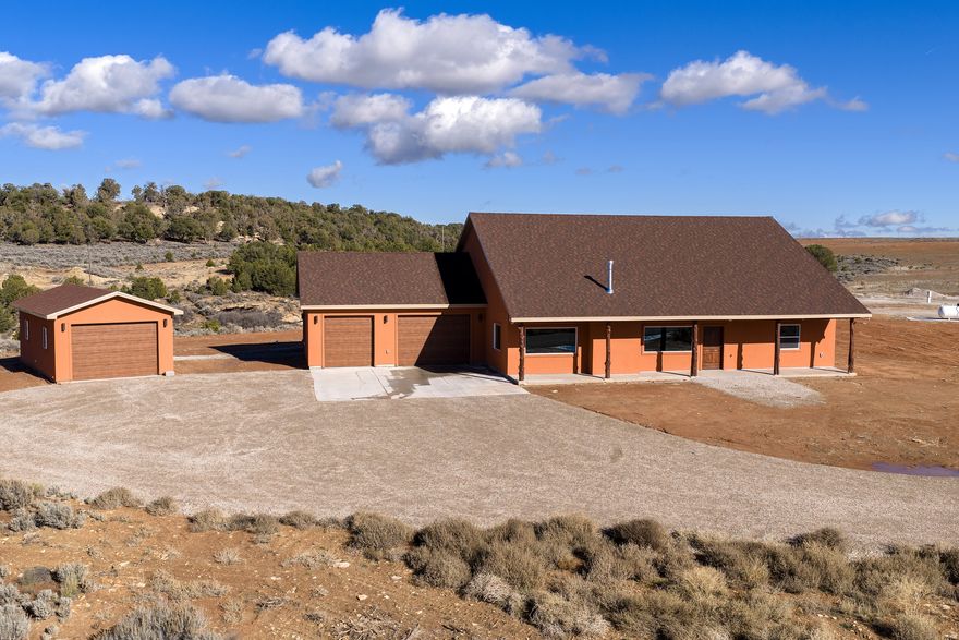 Discover your dream escape just north of Monticello! This beautiful, brand new, open-concept home on 6.46 sprawling acres offers luxury living and exceptional convenience, situated perfectly right off Peter Springs Road. Step inside to discover stunning tile flooring throughout and a chef's kitchen centered around an oversized 5x10 island with full cabinet storage and brand new appliances, including a professional-style 48" NXR propane range featuring a griddle and convection ovens, complemented by a spacious pantry with automatic lighting. Left of the pantry is a centralized equipment room that has a whole house water filter system/water softener/humidifier and an instant hot water circulation system that can be set on a timer. Year-round comfort awaits in the spacious living area with a cozy propane fireplace, floor plug-ins, vaulted ceilings, and a custom built-in bookshelf with cabinets. Conveniently located off the living room is a 3/4 guest bathroom with a built-in tiled shower bench for convenience. The large master bedroom is bathed in natural light and includes a generous walk-in closet and a gorgeous master bath with a dual vanity, built-in makeup counter, and a doorless, curbless walk-in shower with a private L-shaped entrance. Through the large laundry room/mud room with a brand new washer and dryer, built in cabinets, coat hooks, and a hanging rack, you'll find a two-car attached garage with an electric heater, epoxy flooring, and hanging storage racks, which connects to an additional one-car garage. For the ultimate hobbyist or mechanic, there is a large 16x28 detached shop/garage, complete with its own dedicated mini split for air conditioning and heating. Enjoy breathtaking sunrises and sunsets from the front or back covered patios, both equipped with outdoor ceiling fans and lighting. Further amenities include a 50' X 18' premium RV concrete pad with sewer, 50 amp electric, and water hookups.  Property has a shared well with a water right.