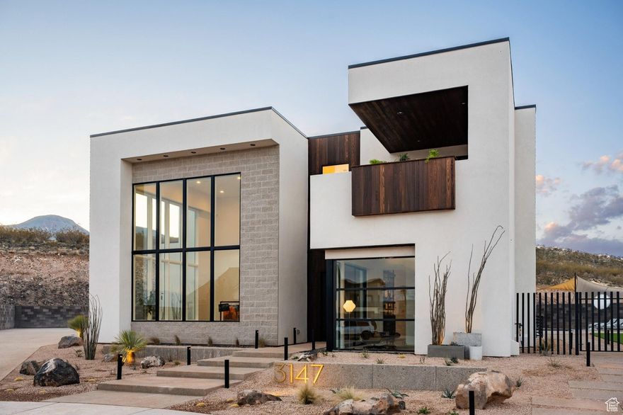 This 2023 Parade Home is a custom 5-bedroom, 6.5-bath stunner that seamlessly merges mid-century charm with Scandinavian elegance. Situated on a .35-acre lot at the end of a quiet cul-de-sac in Copper Rock, it backs onto a serene hillside, providing a private and tranquil escape. The main level showcases a breathtaking great room with soaring 22-foot ceilings and expansive walls of glass. The gourmet kitchen boasts bespoke brass range hoods, rich walnut accents, premium appliances, and a custom oversized island with butcher block seating. A built-in banquette adds a cozy touch, complemented by a striking formal dining area. The thoughtfully designed den offers an inviting space for focused work or peaceful retreat. Upstairs, the primary suite features a private deck and a spa-inspired bathroom with artisan Japanese tile. The suite also includes a generous walk-in closet and an adjacent gym with direct access to the back patio. On the opposite wing, you'll find three en-suite bedrooms and a versatile bonus room. The basement includes a private theater, additional bonus space, a wet bar, and an open area ideal for gaming or relaxed gatherings. Outdoors, enjoy a custom pool with a recessed fire pit and an oversized hot tub. A climbing wall and low-maintenance landscaping round out the backyard oasis. Additional features include 5 garage bays (4 oversized to accommodate recreational gear), custom built-ins, designer imported finishes, and impeccable architectural detailing throughout. Every element was curated for both style and practicality, delivering a refined balance of luxury and comfort. Located just minutes from Copper Rock Golf Course, scenic sand dunes, crystal-clear reservoirs, and the awe-inspiring landscapes of Zion National Park, this home offers a lifestyle that's as adventurous as it is sophisticated. Buyer/buyer agent to verify all information.