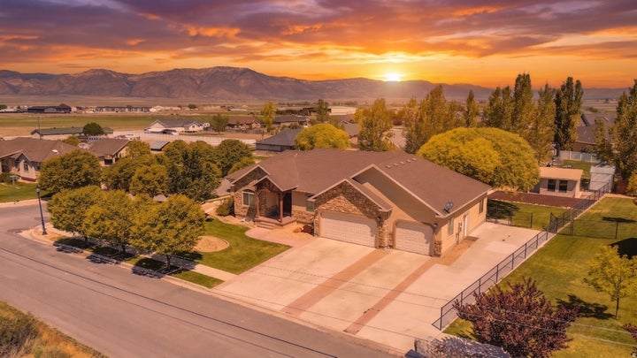 Ranch-style residence featuring a stone and stucco exterior, a three-car garage, and a fenced backyard