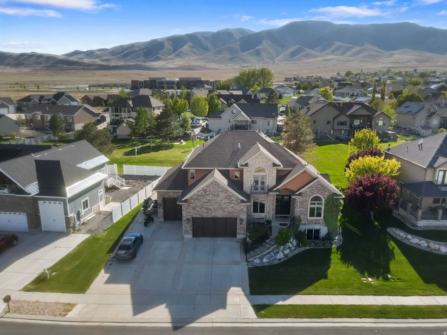Wake up to sweeping lake and mountain views in this exceptional Saratoga Springs retreat, perfectly positioned near Utah Lake and just steps from the marina. Offering over 5,000 sq ft, this beautifully designed 6-bedroom, 4-bath home blends refined comfort, generous space, and serene waterfront living. Sunlight pours through expansive windows, illuminating the open-concept main level where the kitchen, dining, and great room flow effortlessly together-ideal for elegant gatherings or quiet evenings at home. The gourmet kitchen is a true centerpiece, featuring high-end appliances, an oversized built-in refrigerator, premium wood cabinetry, and a convenient pot filler-every detail thoughtfully curated to elevate daily living. The beautiful primary suite offers a private retreat, complete with its own fireplace, a walk-in closet with a view, and a spa-inspired bathroom featuring a relaxing jacuzzi tub. Upstairs, a built-in desk and bookshelves create the perfect space for work or study, while the basement features a dedicated home gym for added convenience and flexibility. Enjoy peaceful mornings and golden sunsets from the front porch, where panoramic lake and mountain views create a truly elevated everyday experience. Just beyond your kitchen door, an HOA-maintained sports court offers space to play and unwind, all without the upkeep! With RV parking and a versatile layout, this home seamlessly blends beauty, function, and location. Opportunities like this are rare-experience lakeside living at its finest in one of Saratoga Springs' most coveted settings.