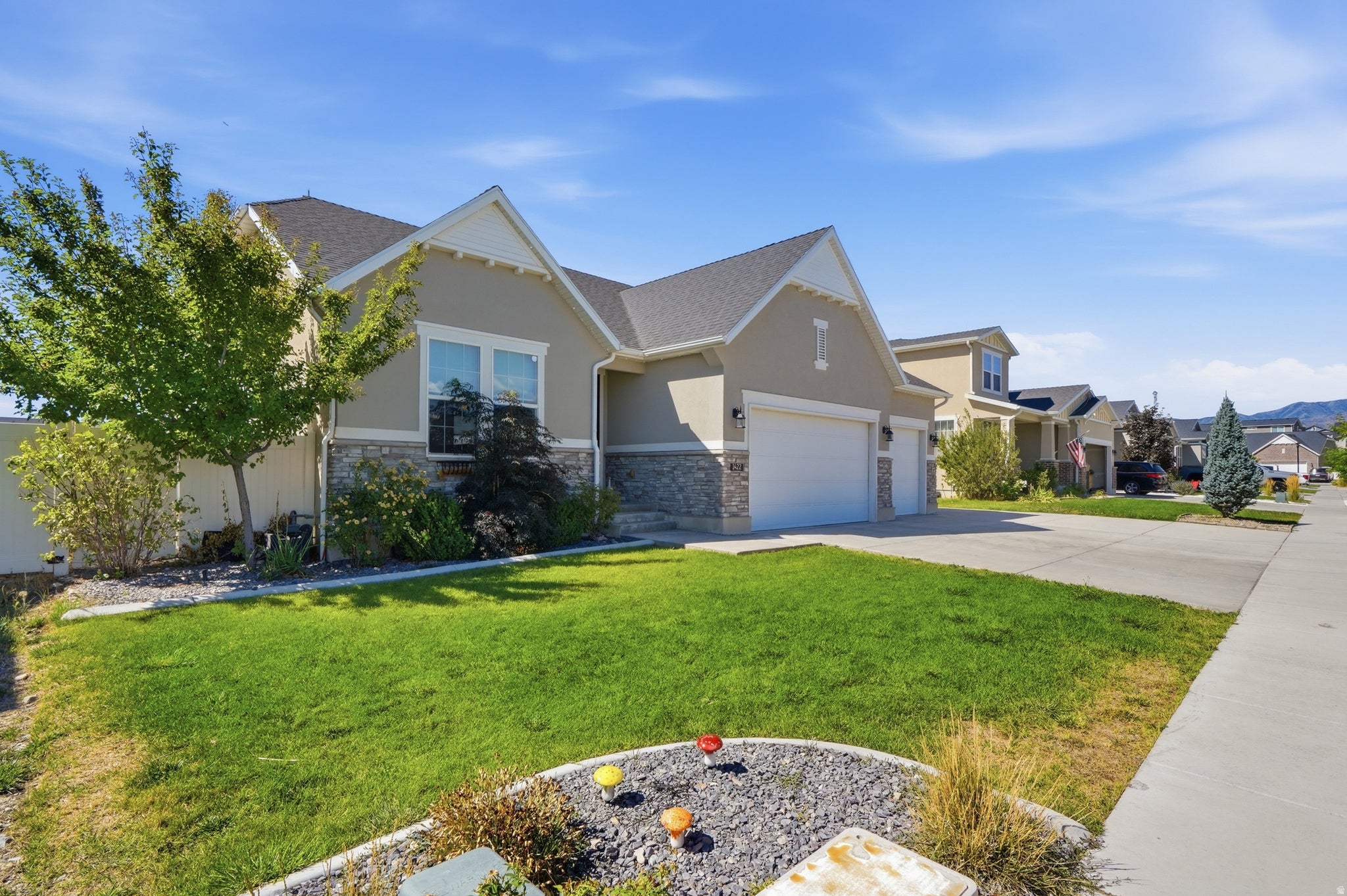 Contemporary residence with a stucco exterior, stone accents, attached two-car garage, and a manicured lawn