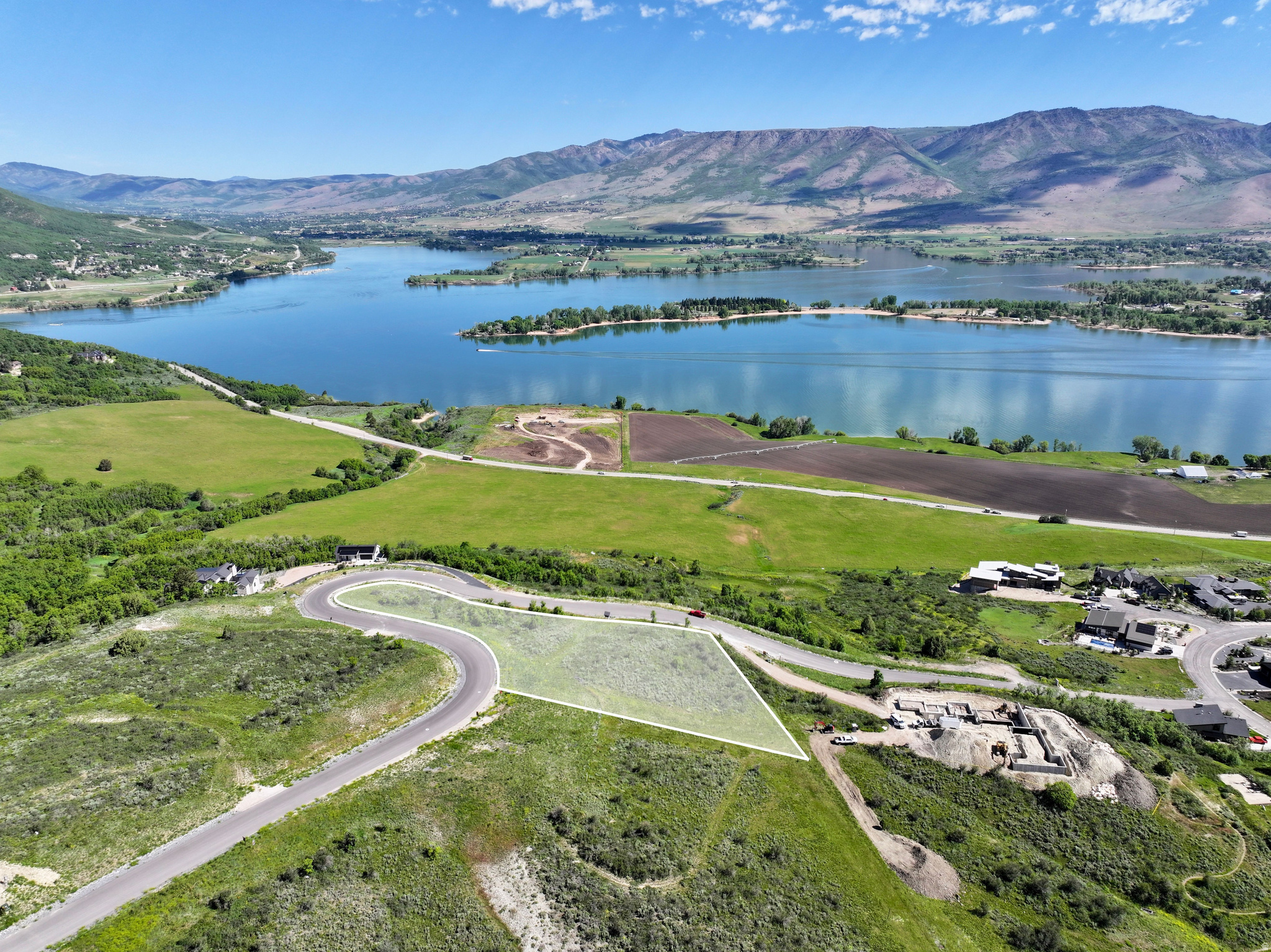 Elevated building lot featuring a clear outline, paved road access, and surrounding natural landscape