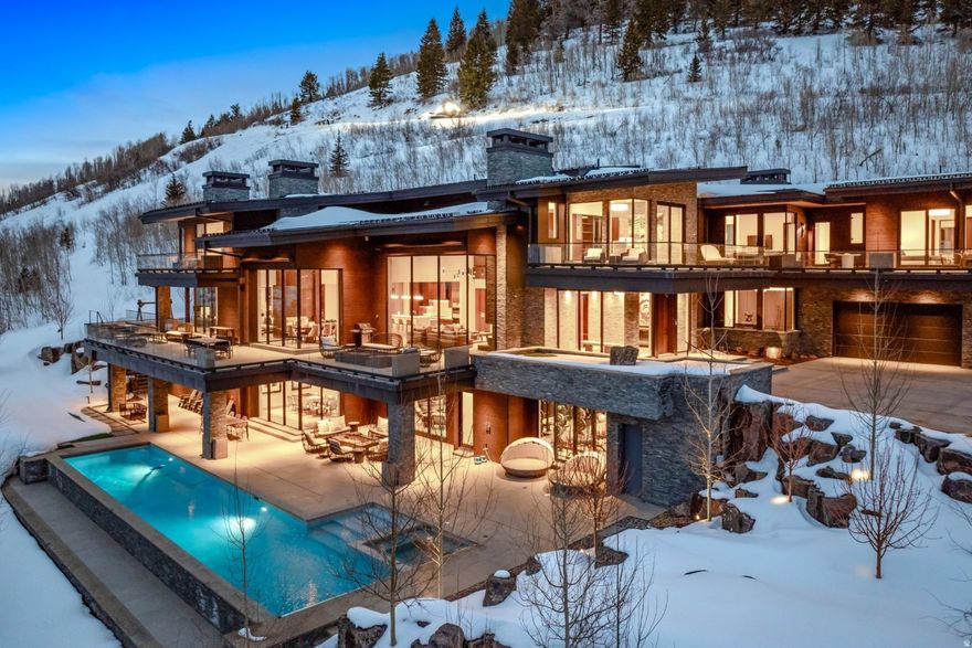 In the exclusive and private enclave of The Colony, this modern contemporary residence is a true architectural triumph. Mountainside with direct ski-in/ski-out access, this estate showcases the visionary design of Rick Otto, Architect, and the masterful craftsmanship of Don Craig Construction. With 14,850 square feet, a heated swimming pool, multiple hot tubs, and ski-in/ski-out accessibility, this home blends luxury and mountain living. Every detail has been meticulously curated, from rich wood floors and striking copper accents to a custom floating staircase and designed lighting. Expansive windows frame ski mountain views, filling the home with natural light and a connection to mountainside living. Designed for luxurious comfort, recreating, and endless entertaining, this residence features six bedrooms, ten bathrooms, two private study/offices, a state-of-the-art gym, a separate yoga/pilates studio, a home theatre, multiple family and laundry rooms, an elevator, exemplary mechanical systems including Savant home technology, Oxygenation system, humidifiers, central air, and radiant heating. The blend of mountain contemporary, the peacefulness and serenity of being on over 7 acres, and the simplicity of skiing directly in and out of the property, make this extraordinary home, an ultimate Park City residence.