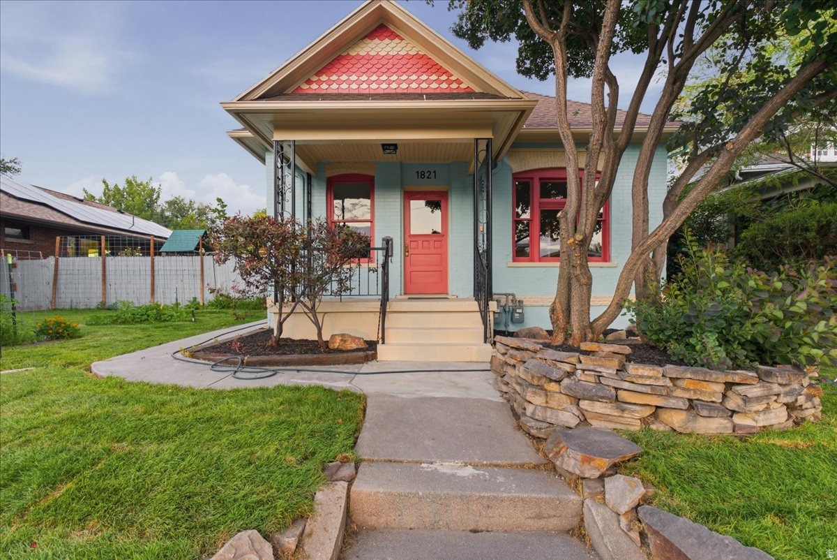 Charming exterior featuring a light blue facade with coral trim accents and a matching front door