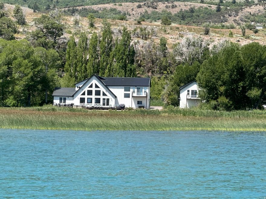 Bear Lake Beachfront Home  201 FT OF LAKE FRONT -Your Private Slice of Paradise. It's time to escape. This presents a great opportunity for a dream vacation home or investment property, as it is already set up & operating as a short-term rental. The main home features 5 spacious bedrooms & 4 bathrooms, offering comfort and space for your family and guests. Enjoy breathtaking panoramic views from every window & unwind on the large deck, complete with a hot tub. The family room provides a perfect gathering space, while the spacious kitchen is great for preparing meals with friends & family. Let the kids escape to the detached garage, boasting a large bunk room and a full bath, offering extra privacy & convenience for everyone.