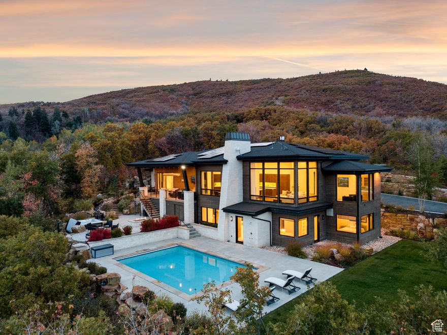 Welcome to the Crown Jewel of The Woods of Parleys Lane. Set within a private, gated community, this 6,299 sq ft mountain contemporary home (designed by Bill VanSickle in 2019), offers exceptional privacy, mountain views, and refined comfort. With 14-foot ceilings and an open, flowing layout, the living spaces center around a double-sided fireplace and extend to a heated deck for year-round indoor/outdoor living. The exterior features a heated saltwater pool, outdoor shower, new hot tub, built-in fire pit, and a peaceful koi pond with a cascading water feature. The luxurious primary suite features its own fireplace, patio, yoga/meditation nook, radiant bathroom floors, steam shower, soaking tub, and generous custom walk-in closet. The separate guest suite includes its own private patio, walk-in closet, and deluxe bathroom with beverage fridge, ready to be stocked for guests.  Flanking the front entry are two offices with ensuite baths that can easily convert to bedrooms or guest space with the included Murphy bed.  The lower level includes a large family/game/media room, three additional ensuite bedrooms with custom walk-in closets, a large laundry room, recently expanded gym, and connects to a 3-car garage with adjoining workshop - ideal for skis, bikes, or creative projects. The current owners have invested significantly in thoughtful upgrades, including extensive landscaping to ensure full property insurability, expanded gym space, a new Sonos whole-house audio system, brand new washer & dryer, and a brand new hot tub.  Additional features include a solar panel system, whole-house humidifier, Nest thermostats, partially heated driveway, and ALL FURNITURE NOW INCLUDED IN THE SALE PRICE.   Situated within the Park City School District and just 15 minutes to world-class skiing and 25 minutes to the international airport. Residents also enjoy a private trail system maintained year-round that connects to the Jeremey Ranch dog park and community pond.