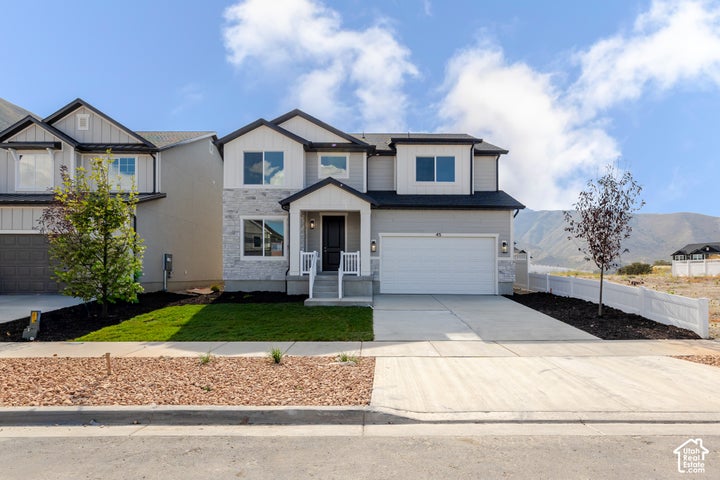 Two-story exterior featuring a stone veneer facade, horizontal siding, attached two-car garage, covered entryway, and…