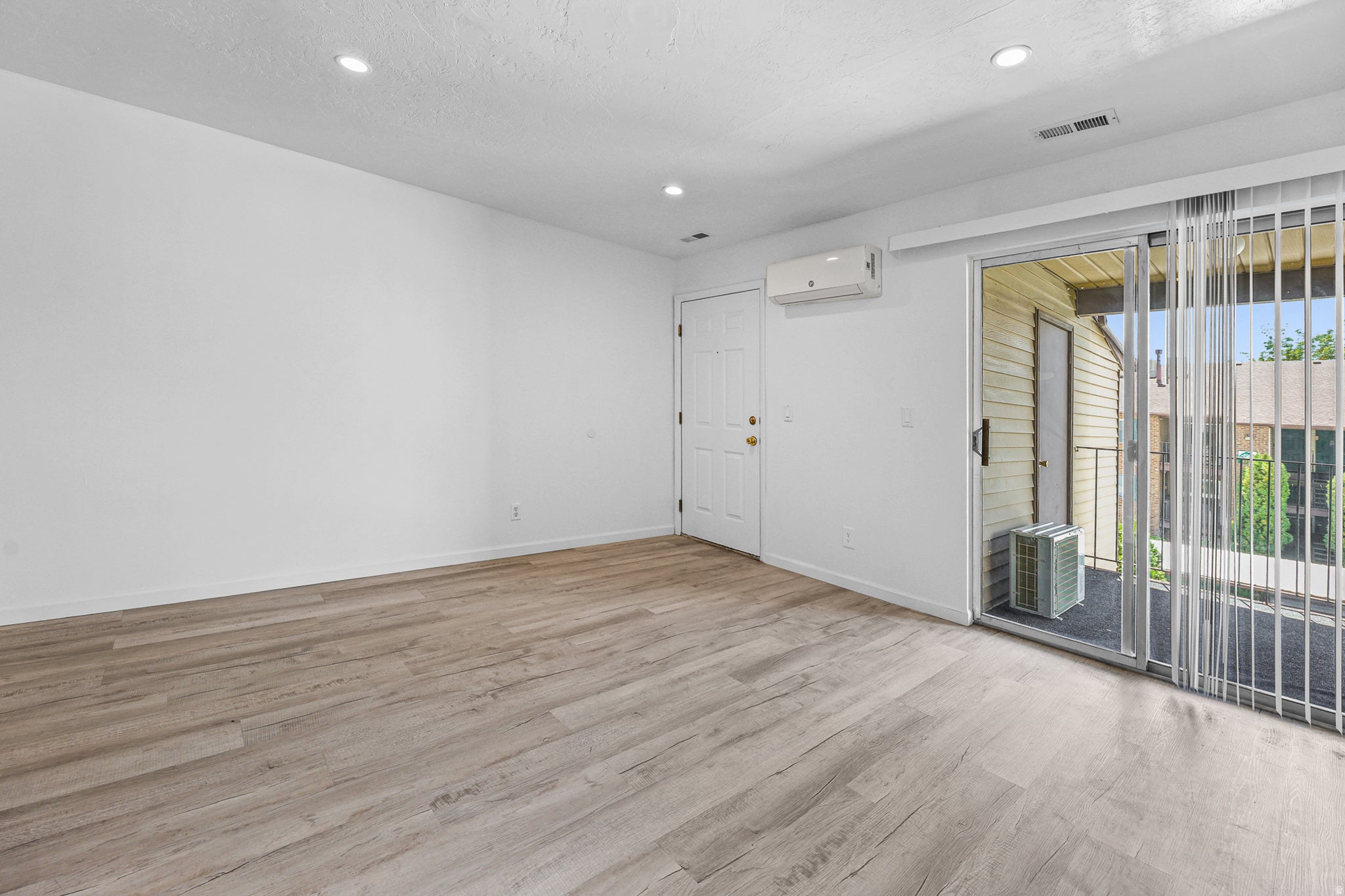 Spacious interior featuring wood-finish vinyl flooring, white walls, recessed ceiling lighting and mini split ductless HVAC system