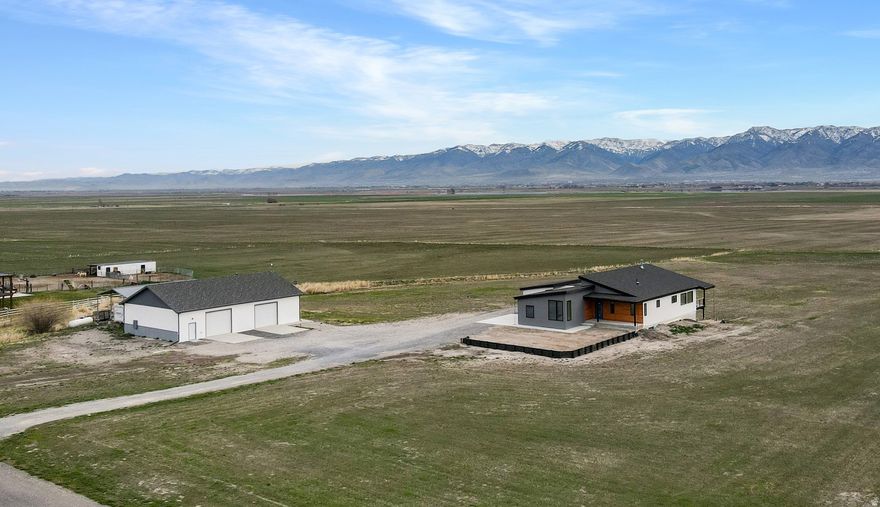 Stunning modern style rambler on 6.05 acres with sweeping views! Thoughtfully designed 4,021 sq ft Smart Home with 3/4" thick red oak hardwood flooring, vaulted ceilings, and an open great room with abundant natural light is anchored by a Vermont Castings wood burning stove. On top of that, the data room features a full audio system, surround sound in the great room and speakers throughout the home which can be independently controlled  perfect for both everyday living and entertainment. Gourmet kitchen includes quartz countertops, a THOR 6-burner gas cooktop with pot filler, double ovens, and a butler pantry for added storage and functionality. Spacious owner's suite with walk in closet, has a bath with dual vanities, LVP flooring, separate water closet, and walk in shower. Bedroom 2 offers ample room as well as a walk in closet. Oversized 3 car attached garage is wired for EV charging. Unfinished basement offers room to expand; proposed plans available. The exceptional 2,400 sq ft heated shop: 2x6 construction on monolithic slab, 12' walls, fully insulated (R 60), bathroom, W/D hookups, 400 amp power, and two 10' x 10' bays ideal for hobbies, business use or serious storage needs. Covered RV parking with hookups. This home is a rare blend of modern comfort, quality construction, and wide open space with unbeatable views. Buyer to verify all.