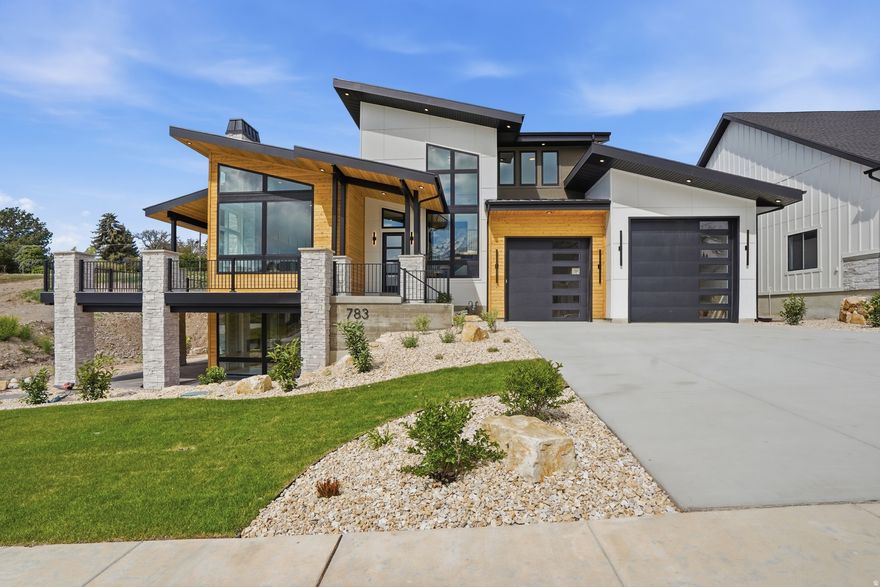 **OPEN HOUSE** Agent will be available at 793 N 150 E, during open house hours.  Welcome to this stunning modern home that perfectly blends style, space, and functionality with a warm, inviting feel throughout. From the moment you step inside, you're greeted by an open, airy layout paired with high-end finishes that make every space feel both elegant and comfortable. Enjoy true main-level living with a spacious primary suite, complete with its own private laundry for added convenience. The heart of the home is a chef's dream kitchen featuring an impressive 60 sq ft island, an 8-burner stove with four ovens, a working pantry with a beverage cooler, and plenty of room to gather, entertain, and create lasting memories. Car enthusiasts and hobbyists will appreciate the rare 3.5-car garage with soaring 16-foot ceilings-offering exceptional space for storage, toys, or even a workshop.  Also included is a 220 outlet, and a washing station.  Step outside to 682 sq ft of covered wraparound deck space, complete with a fireplace-perfect for year-round outdoor dining, relaxing, or taking in the views. Downstairs, a 610 sq ft covered patio provides direct basement access and even more room to unwind or entertain. Upstairs, two generously sized bedrooms each feature their own private ensuite bathrooms, making them ideal for guests or family members. A cozy loft adds flexible space for a reading nook, home office, or play area. The fully finished basement is designed for entertaining, offering three additional bedrooms-one perfectly suited for a future home theater-along with three bathrooms, a second laundry area, and a large family or activity room. Outside, enjoy the added value of full front yard landscaping and partial backyard landscaping, along with built-in concrete planter boxes ready for your personal touch-creating a move-in-ready outdoor space that complements the home's beautiful design. This thoughtfully designed home offers versatility, comfort, and luxury at every turn-don't miss your opportunity to make it yours. ***Photos of previously built Denali***