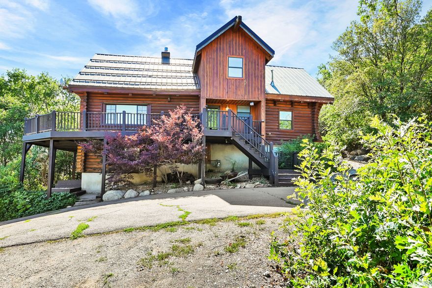 This unique and rustic home is the perfect opportunity to own your own mountain retreat in the Ogden Valley! This log home sits on a 1-acre lot and features panoramic views of the Wasatch Mountains and valley floor. It also has a direct view of James Peak, home of Powder Mountain ski resort. The large wrap-around front porch is a perfect place to enjoy the views and take in the outdoors. Step inside and find a main level that offers a spacious living area with high ceilings, and a kitchen with built in wine fridge and plenty of cabinets for storage. You'll also find 2 bedrooms and a full bathroom. The primary suite on the upper floor features a walk in closet and a large primary bathroom, and a balcony. The lower level features an additional living room, a mudroom area with storage, two additional bedrooms, another full bathroom, and an additional storage area. The property is located less than a mile from Nordic Valley Ski Resort, 20-minutes from Powder Mountain, and 25-minutes from Snowbasin.