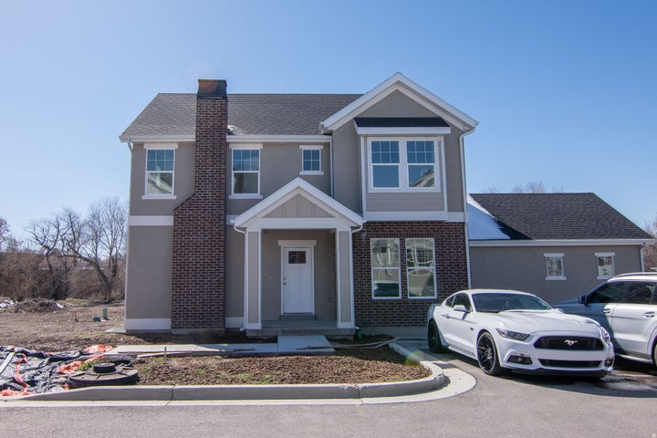 Two-story residence featuring a gray stucco and brick facade with a prominent brick chimney
