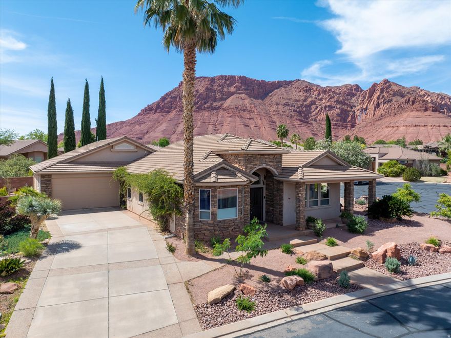 This fully custom home, loaded with thoughtful amenities and stunning red mountain views, is ideally located near Tuacahn Amphitheatre, Snow Canyon State Park, and Black Desert Resort. An extensive network of walking and biking trails leads directly from your front door to the Mojave Desert tortoise reserve, Snow Canyon trail system, and into Black Desert and beyond.  Inside, you'll find nearly 2,400 sq ft of charm and quality craftsmanship rarely found in builder-grade homes. Features include high-end engineered hardwood flooring throughout, an oversized primary suite, and a climate-controlled storage room in the garage. The oversized 2-car garage plus shop offers the square footage of a 3-car garage and could easily be converted into a 4-car tandem garage by removing the storage room.  The beautifully updated kitchen is designed for both function and style, featuring pull-out drawers in all lower cabinets, Taj Mahal quartzite (genuine stone) countertops, a workstation sink with a solid brass faucet, and abundant lighting.  Step outside to the wraparound porch and take in breathtaking views of the red mountains and The Citadel, or simply relax in the quiet, private, and friendly neighborhood.  Recent updates-including landscaping, HVAC, water heater, and water softener-offer low maintenance and peace of mind. With thoughtful details and unique touches throughout, this home is one you'll want to experience in person.