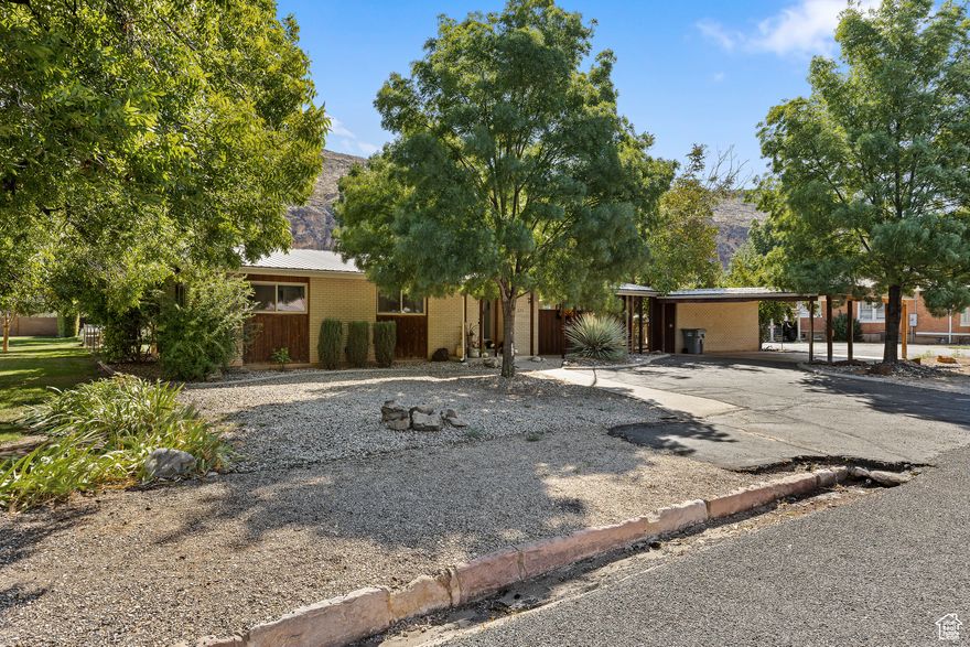 Hard-to-find downtown Hurricane home on South Main that blends nostalgic charm with thoughtful updates. Just one block from Main Street Caf, this single-level home (with a massive cold-storage basement cellar) sits on a spacious lot with no HOA or CC&Rs. Inside, recent upgrades include new carpet, fresh paint, durable LVP flooring, and recessed can lighting for a bright, modern touch. Enjoy the double-sided natural gas fireplace in the living and dining areas, a cozy wood-burning stove, built-in desks and storage, and convenient appliance/sewing closets. The home also features several new HVAC mini-split systems and some upgraded plumbing. Step outside to a fully fenced backyard with mature trees, grapevines, and fruit trees (fig, peach, plum, and pomegranate). Relax under the large covered patio with evening shade and views of the Hurricane Cliffs, or gather around the flagstone fire pit. A pull-through driveway, 2-car carport with extra storage closets, and additional parking make daily living easy. Current zoning is residential, but the property lies within the "Downtown" category of the city's General Plan Land Use Code-an area under review for future opportunities. The home is OCCUPIED, shown by appointment only. *All information is deemed reliable but not guaranteed, buyer to verify all.