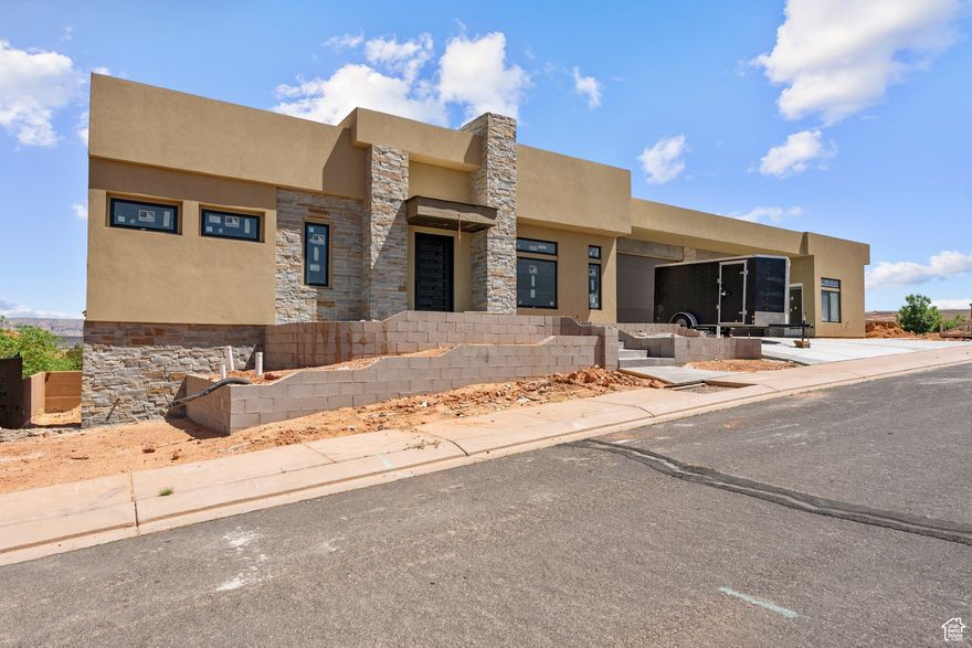 Nearing completion in the highly desirable Sand Hollow Golf Course community, this stunning home sits on a spacious corner lot with endless possibilities. Designed for versatility, it features three distinct living areas-including a full walk-out basement with its own kitchen, 3 bedrooms, and a multi-purpose room that's perfect for a theater, gym, or game room. Ask about avail. options for customizing this space to suit your needs. The main level features 4 bedrooms, 4 bathrooms, and a private casita. The home is plumbed & ready for an elevator & includes a 4-car garage with 10' doors. Premium finishes include stunning hardwood flooring throughout the main living areas (Volterra Collection - Avellino European Oak), tile flooring & tile showers with glass enclosures in all bathrooms, and Moen fixtures throughout. Step outside to a covered deck & rooftop terrace offering panoramic red rock & golf course views. The spacious backyard is pool-ready and includes a separate entrance to the lower level ideal for added privacy or rental potential. A perfect blend of luxury, flexibility, and resort-style living in Southern Utah.