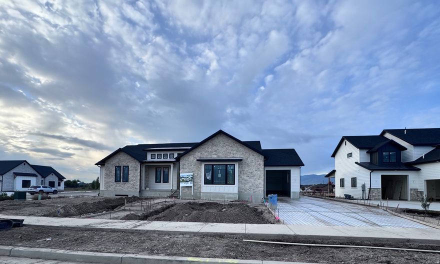 Home Under Construction  Modern farmhouse design with a blend of contemporary and rustic elements. The exterior showcases white board and batten siding complemented by stone accents, black-framed windows, and dark roofing. The house has a welcoming entryway with a covered porch and large glass doors.  TriCo Construction is the home builder